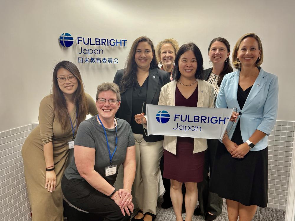 A group of seven people posing for a picture with the Fulbright logo