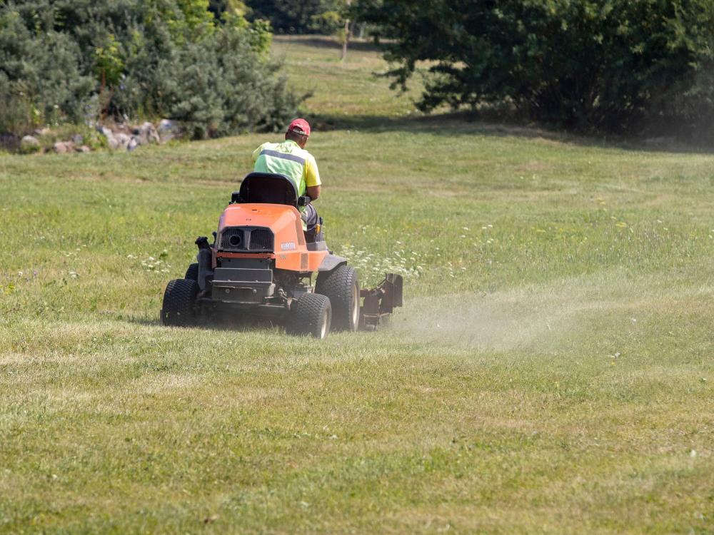A person operates a riding lawnmower.