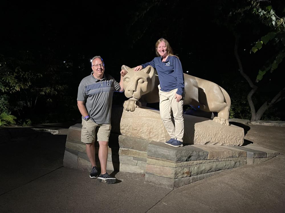 couple poses next to penn state lion statue at night