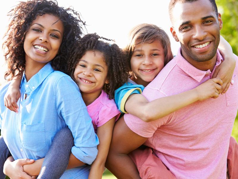 Family with two parents and two children smiling at the camera.