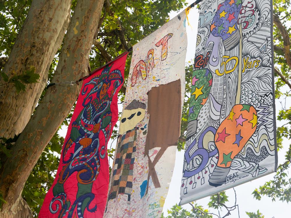 Three colorful banners sway high in the breeze above the street