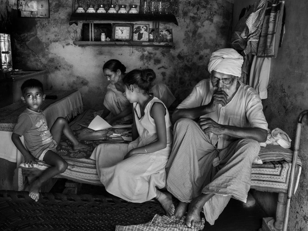 A black and white photograph of people sitting on a bed
