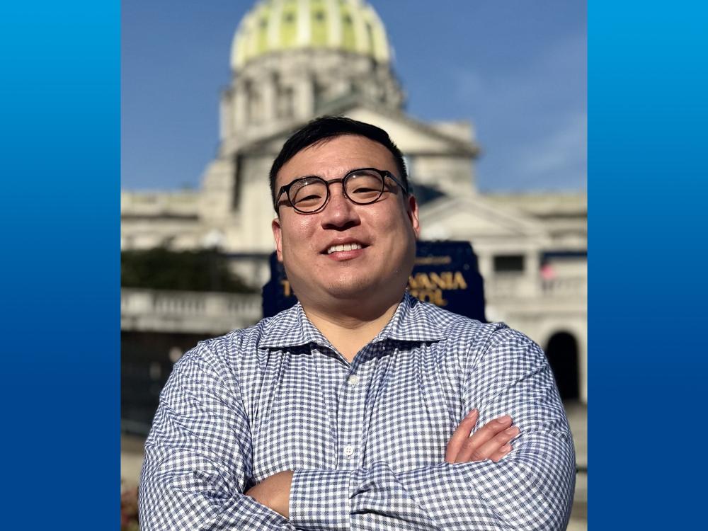 Person in Harrisburg looking at camera, with a large government building in the background