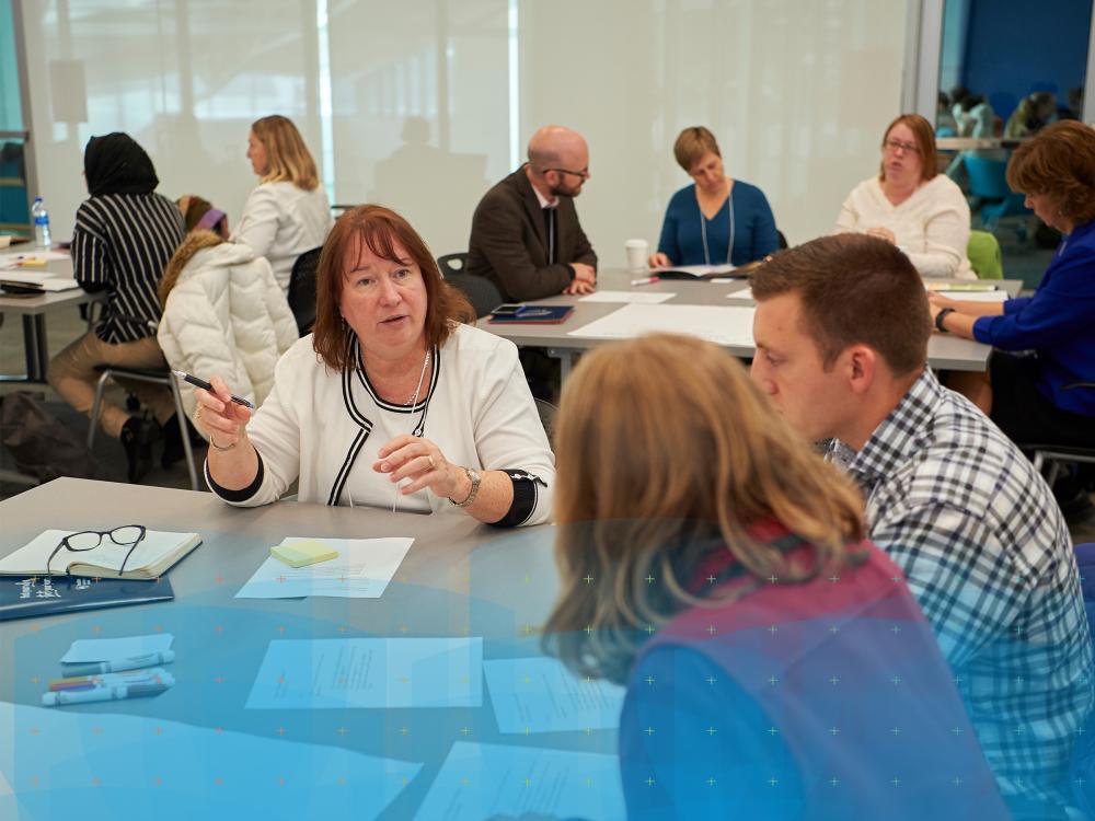 People having a discussion at a table with a blue graphic design overlay