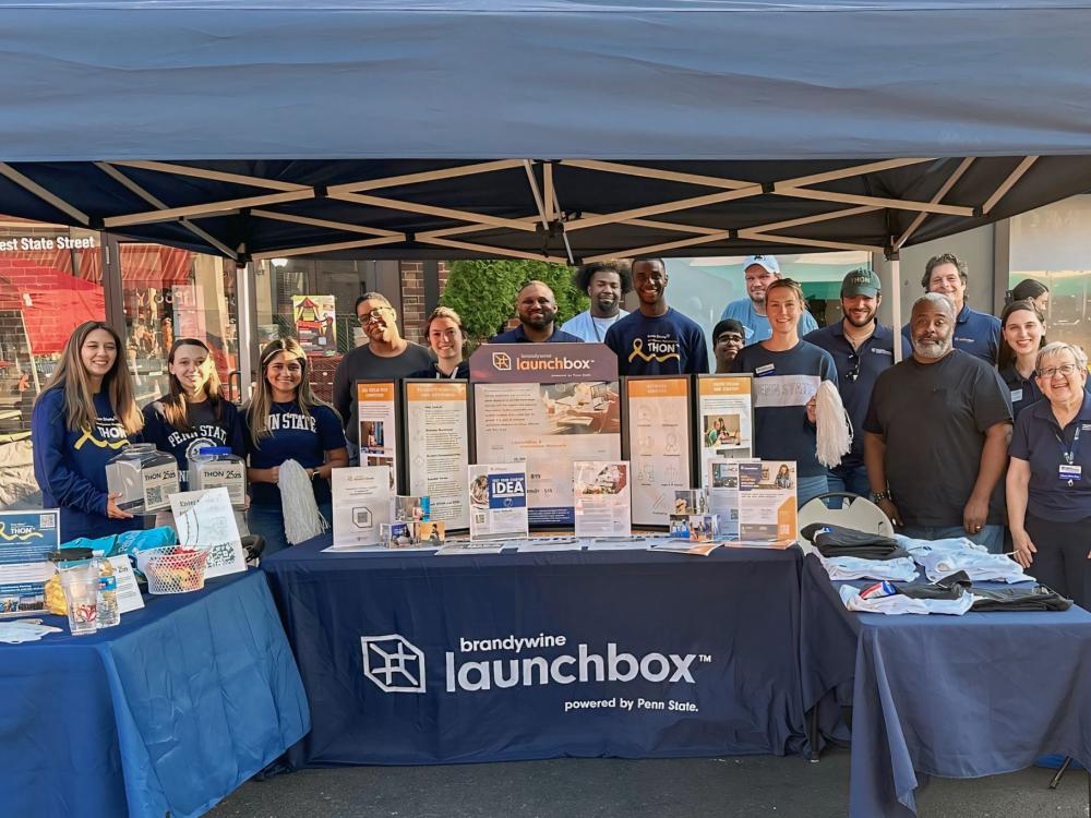 a group of students, alumni and staff behind a table that advertises the Brandywine LaunchBox