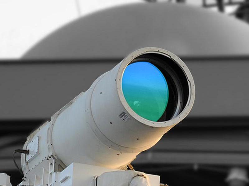A close-up photo of a laser housed at Penn State's Electro-Optics Center. The round lens is pointed to an object in the distance and the sun reflects off that lens.