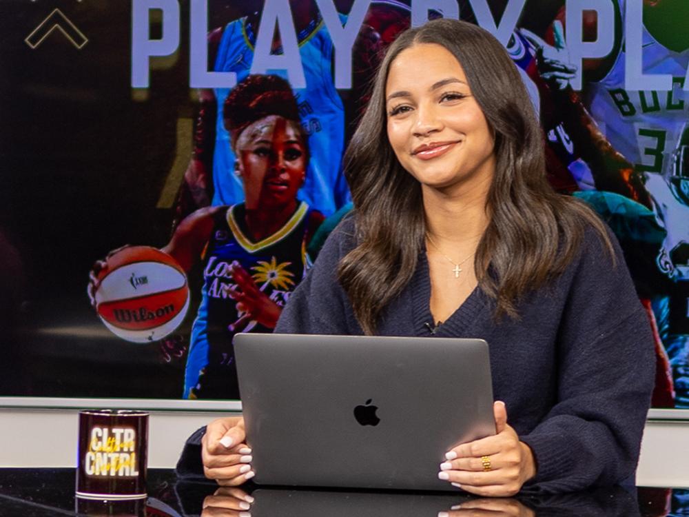 Student sitting at news desk with monitor behind her
