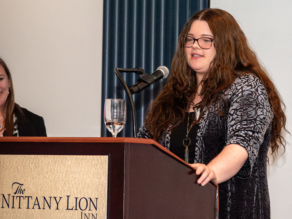 Kate Robeson-Grubb at a podium; speaking into a microphone.