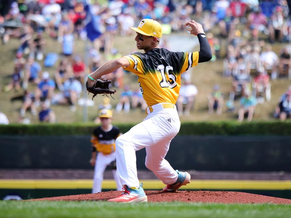 A baseball pitcher in a yellow uniform delivers a pitch