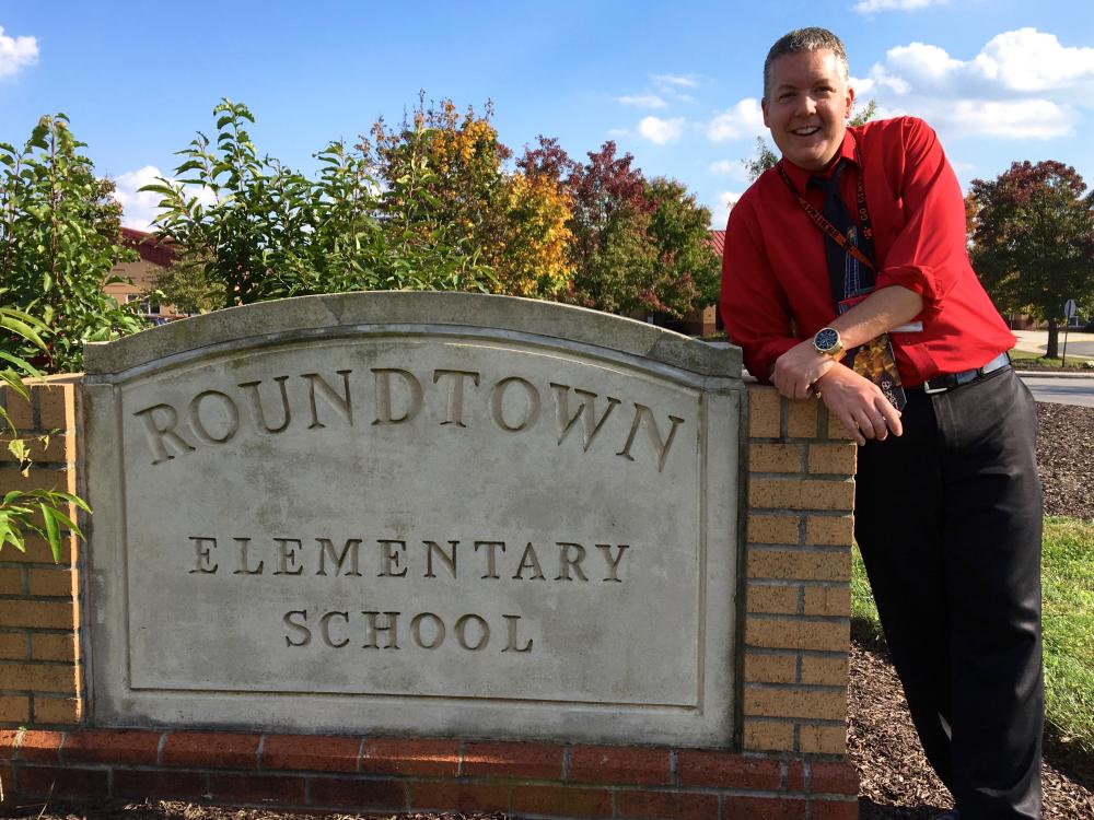 Man wearing red shirt leans against concrete sign