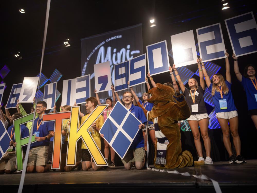 Several students – and the Penn State Nittany Lion – hold up numbers that spell out $6,413,950.26.