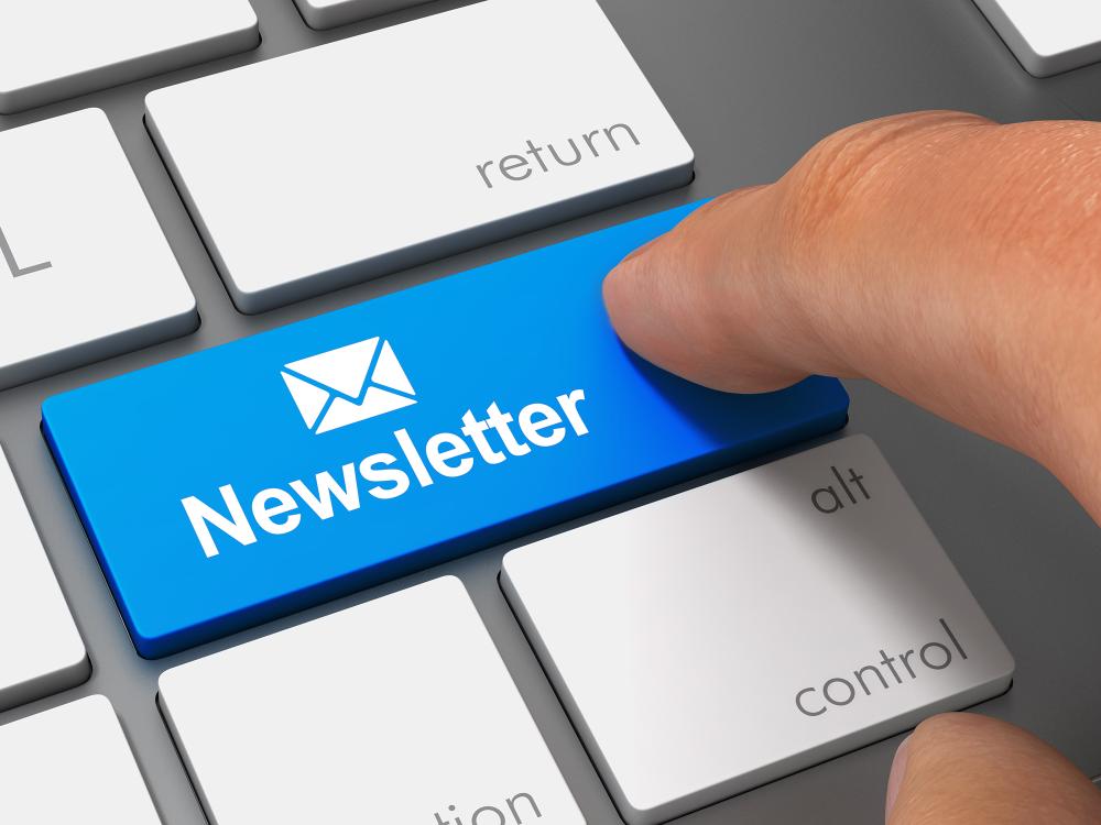 Close-up of a computer keyboard with a blue key labeled Newsletter featuring an envelope icon, being pressed by a finger.