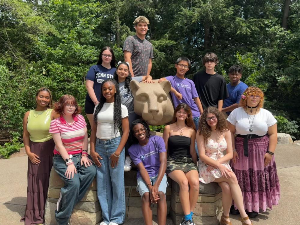 13 high school students pose for a photo at the Nittany Lion Shrine.