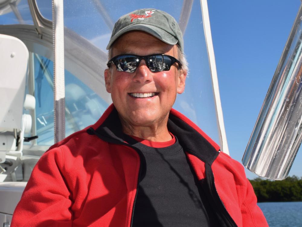 A photo of Jeff King with sunglasses and a hat, sitting on a boat.