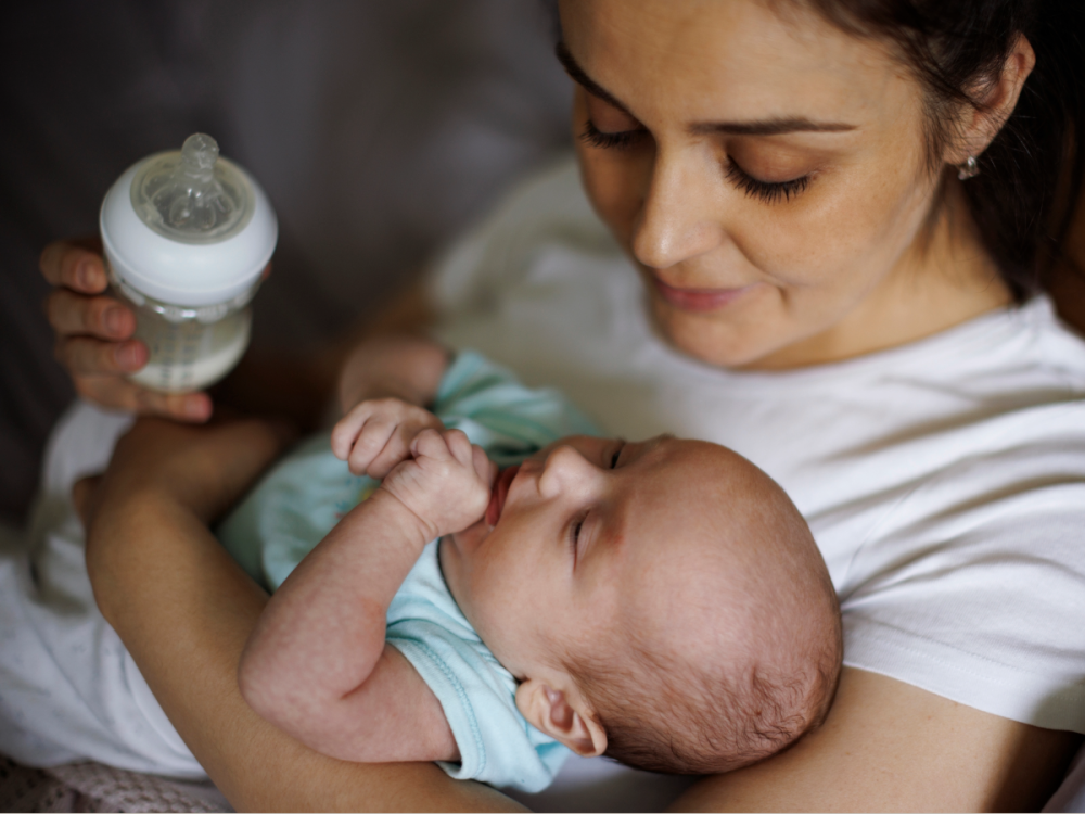 Woman holding her baby and holding a bottle to feed them