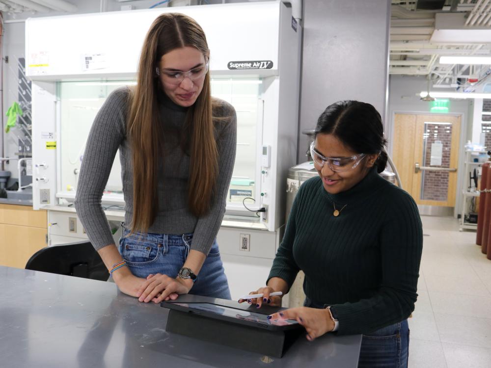 Two students discuss lab sustainability at a table