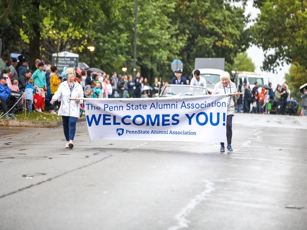 Penn State alumni carrying Homecoming banner during parade