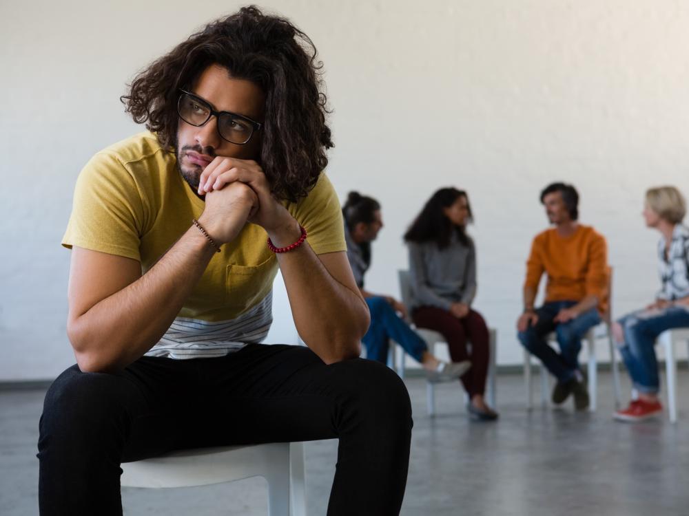student sitting away from group talking together