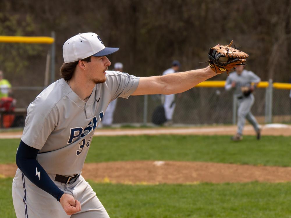 Penn State baseball player Brayden Patton, wearing a gray uniform and cap, pitches the ball during a game on a sunny afternoon.
