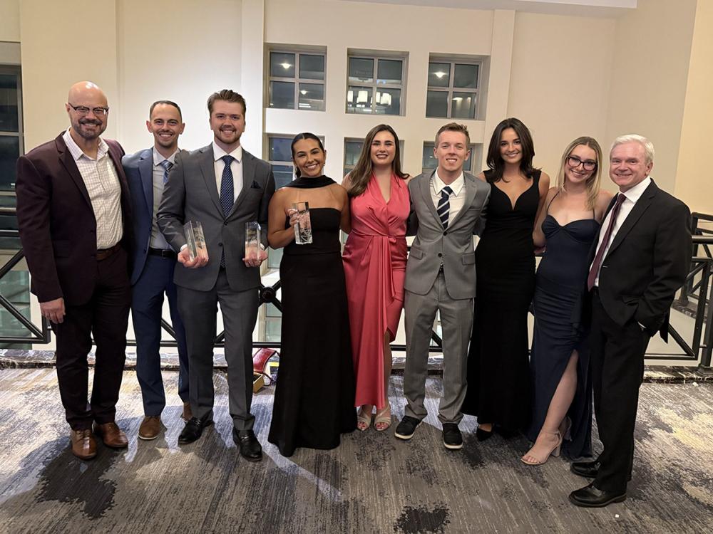 A group of well-dressed people posing for a photo while holding some awards.