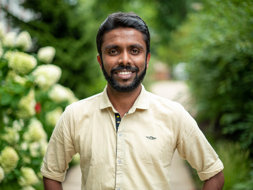 Chandima Sudantha Subasinghe smiling outside in front of greenery.