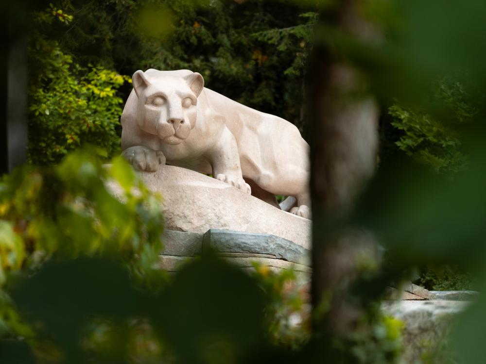 A picture of the Nittany Lion shrine through green leaves