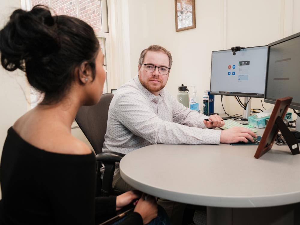 Adviser at computer talking to student