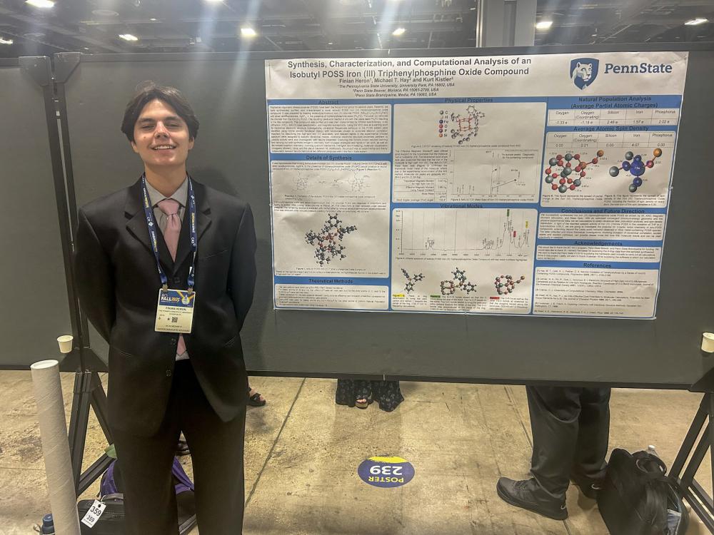 A photo of a student standing next to a poster board presentation