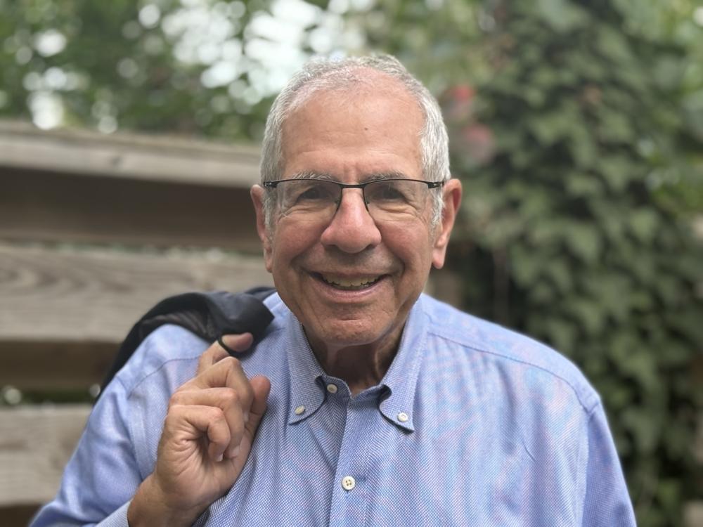 headshot of Elliott Weinstein standing outside near a fence and trees