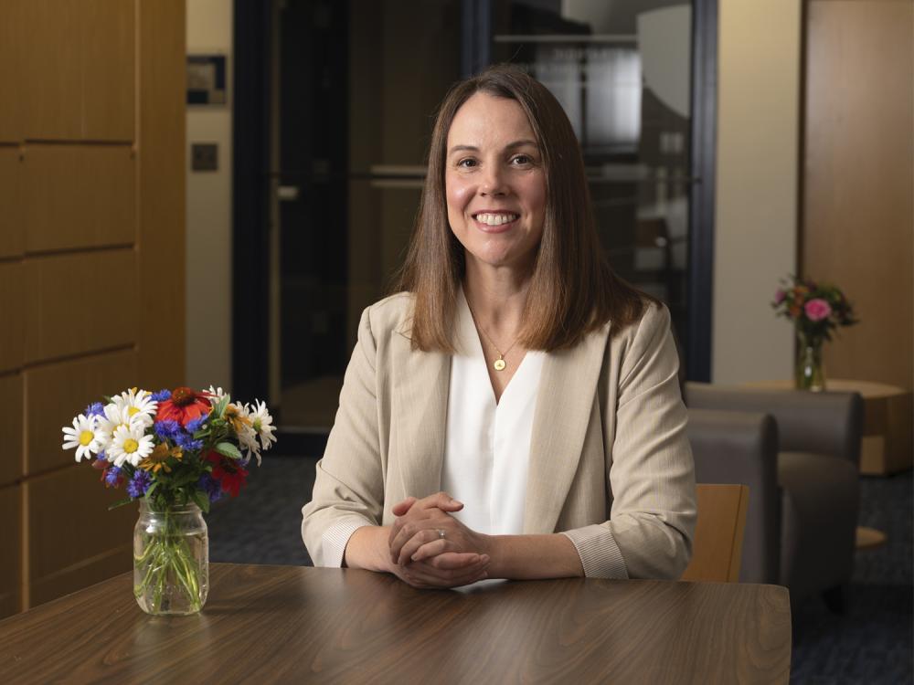 MBA student Jessie Whiteman sits at a desk with a vase of flowers next to her.