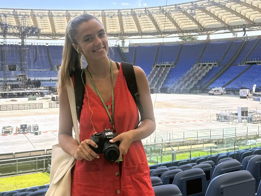 Woman standing in an arena holding a camera.