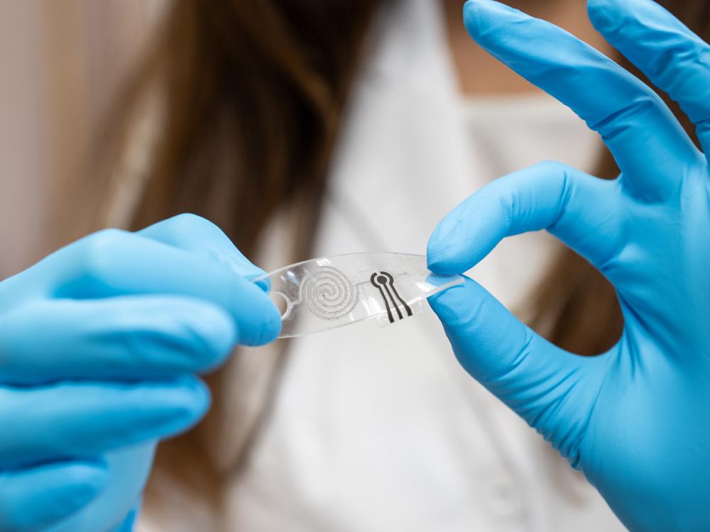 Hands in blue gloves holding a flexible sensor