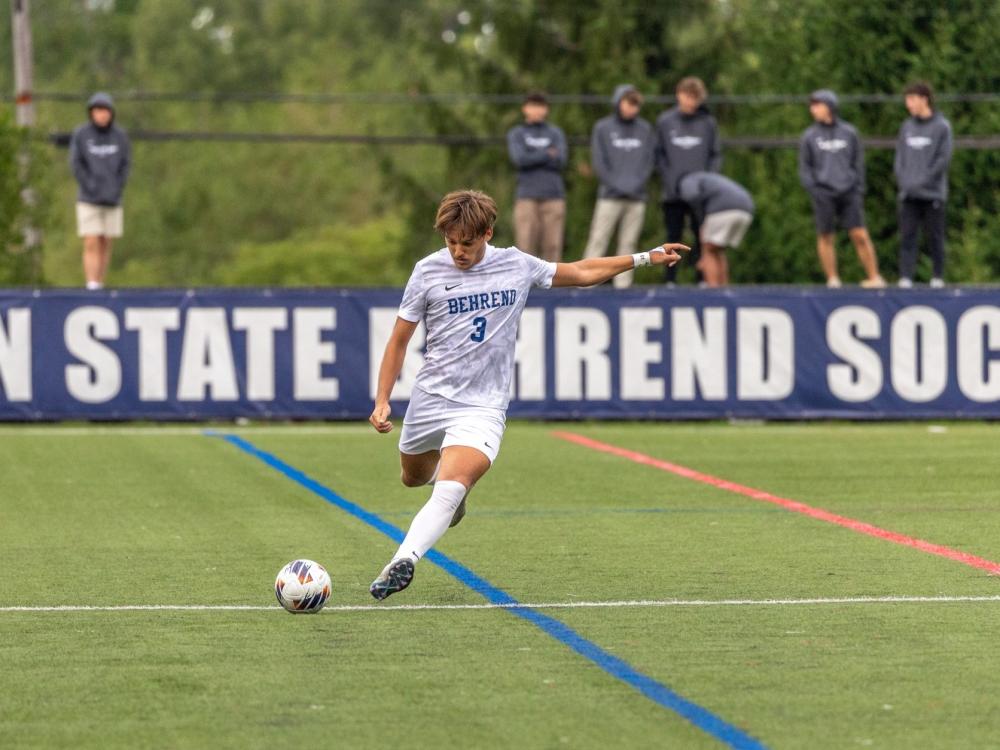 A member of the Penn State Behrend men's soccer team kicks the ball.