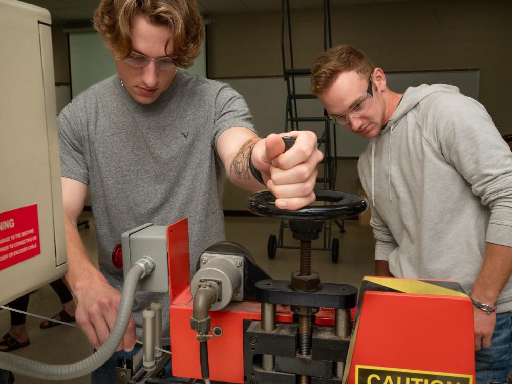Two polymer engineering technology students at Pennsylvania College of Technology troubleshoot some equipment in the college's extrusion lab.