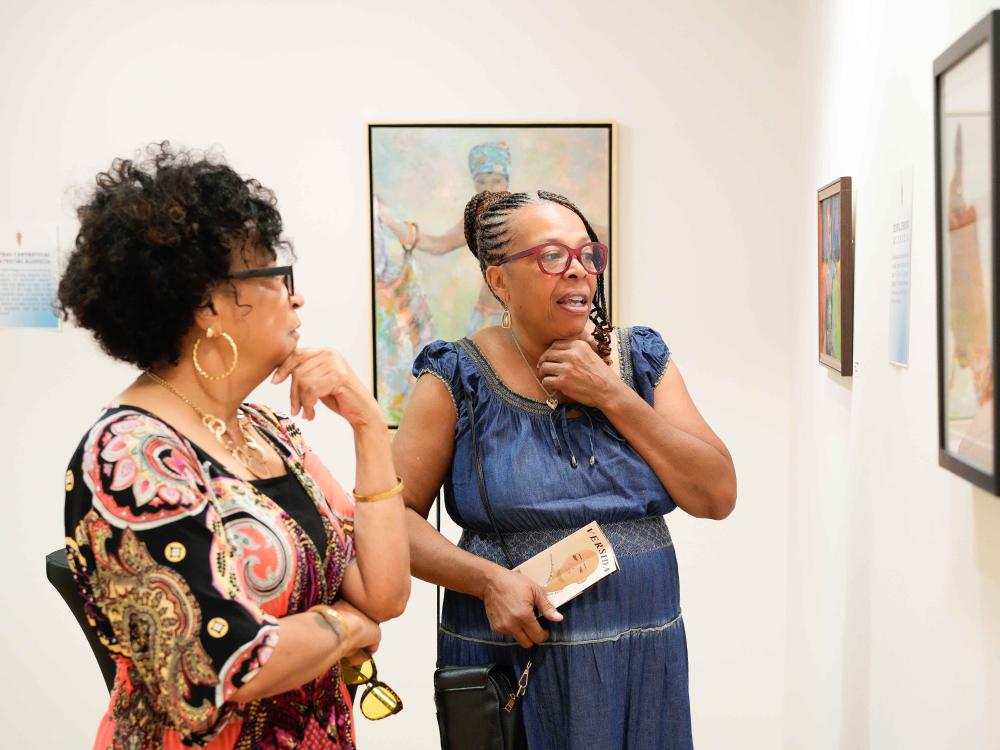 Two women viewed from the side as they survey art on the wall in a museum