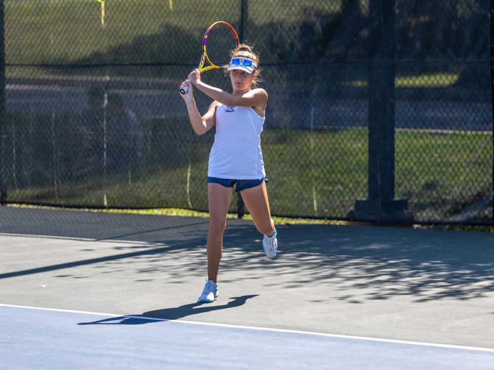 A member of the Penn State Behrend women's tennis team hits a backhand.