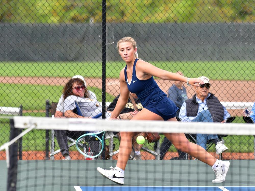 A member of the Penn State Behrend women's tennis team hits a forehand shot.