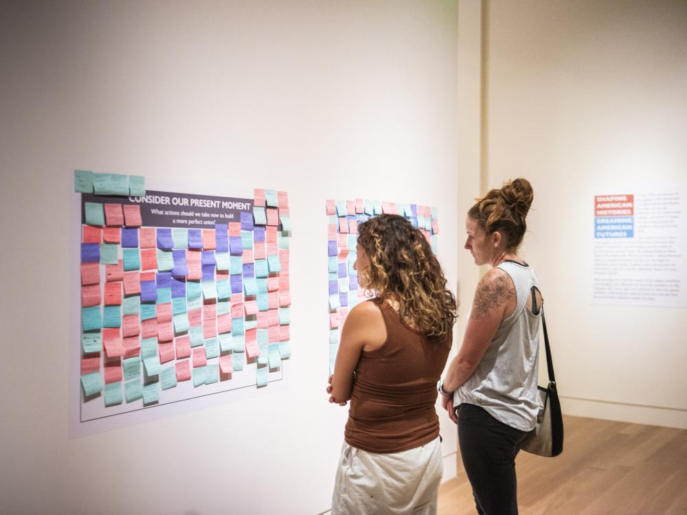 Two women looking at a wall of colorful sticky notes