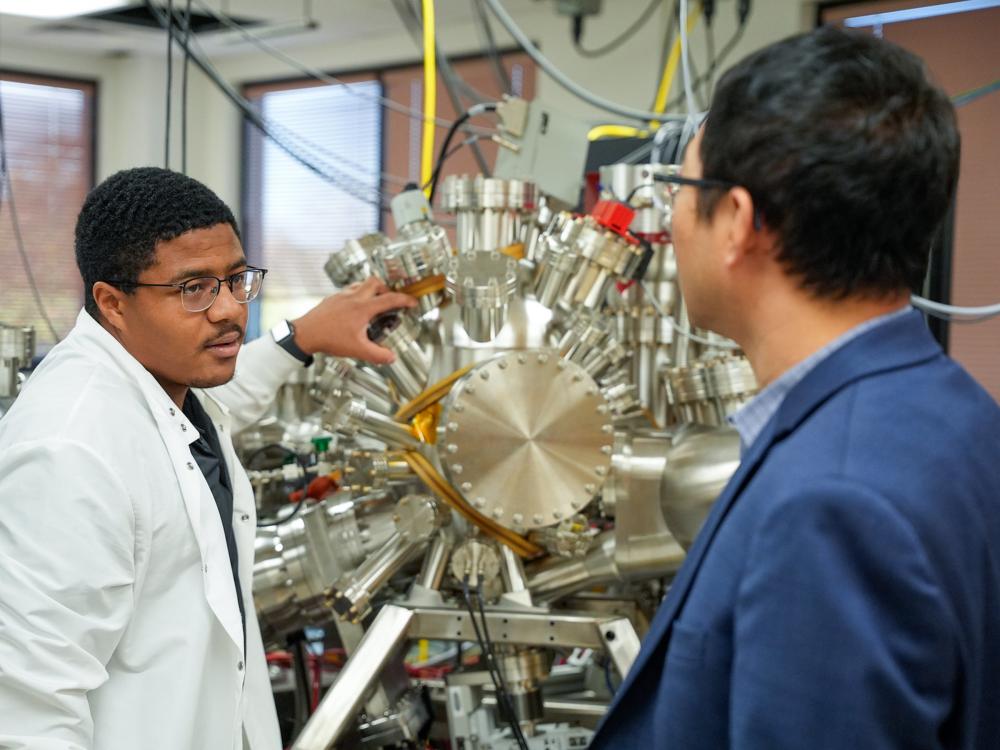 Person explaining to another person the science behind a large vacuum chamber for nuclear engineering research.