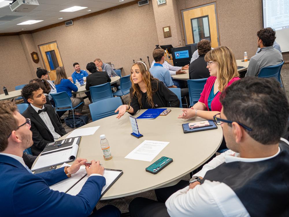 Students and business representatives sit at round tables during a networking event at the Penn State Harrisburg Sales Competition