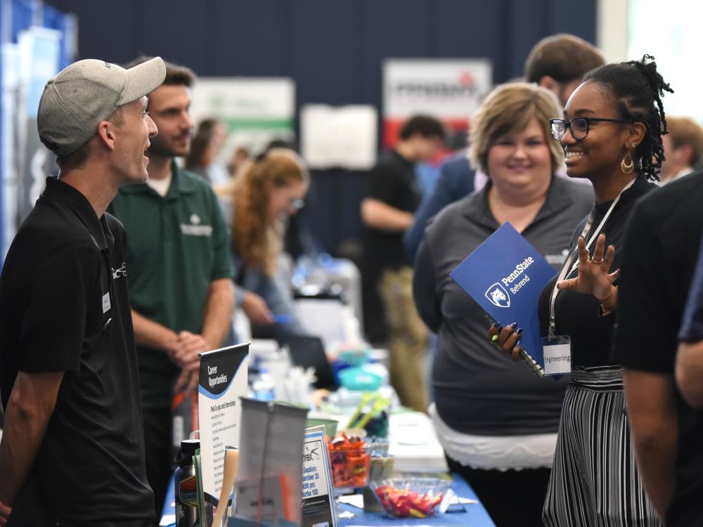 A recruiter talks with a student at Penn State Behrend's fall career fair.