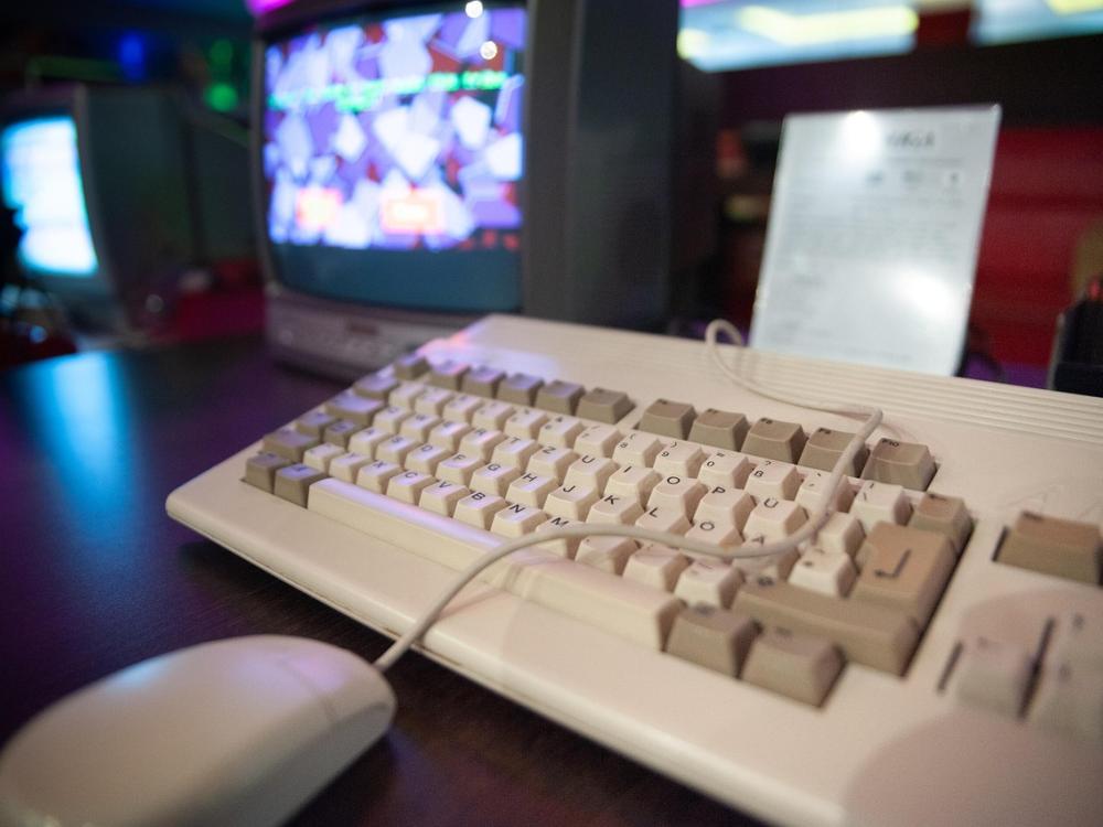 vintage keyboard and wired mouse in front of cathode ray tube computer screens