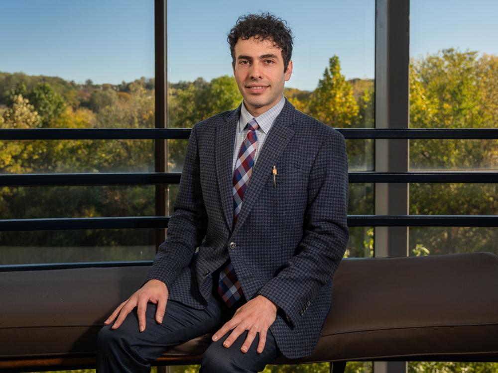 Engineering management associate professor Ashkan Negahban sits in front of a view overlooking trees on Penn State Great Valley's campus