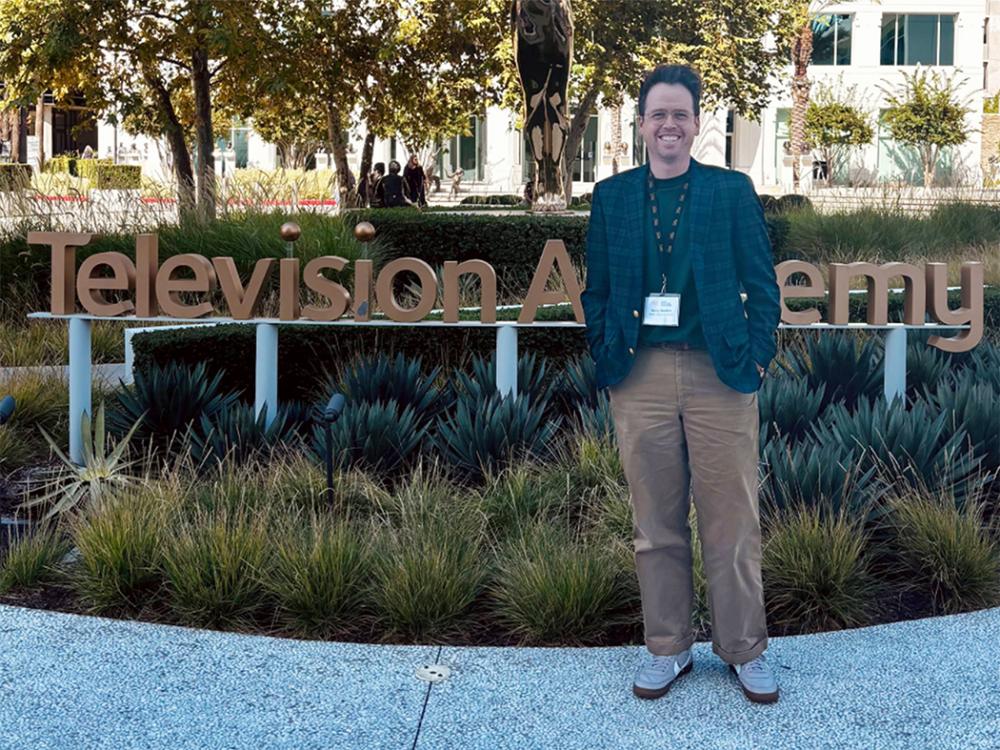 Smiling man in glasses, green sport coat an slacks