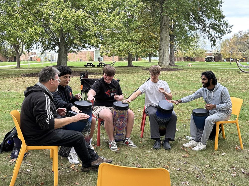 A group of people sit in a circle with drums.