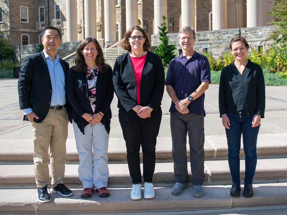 A group of five people stand on a step in front of Old Main
