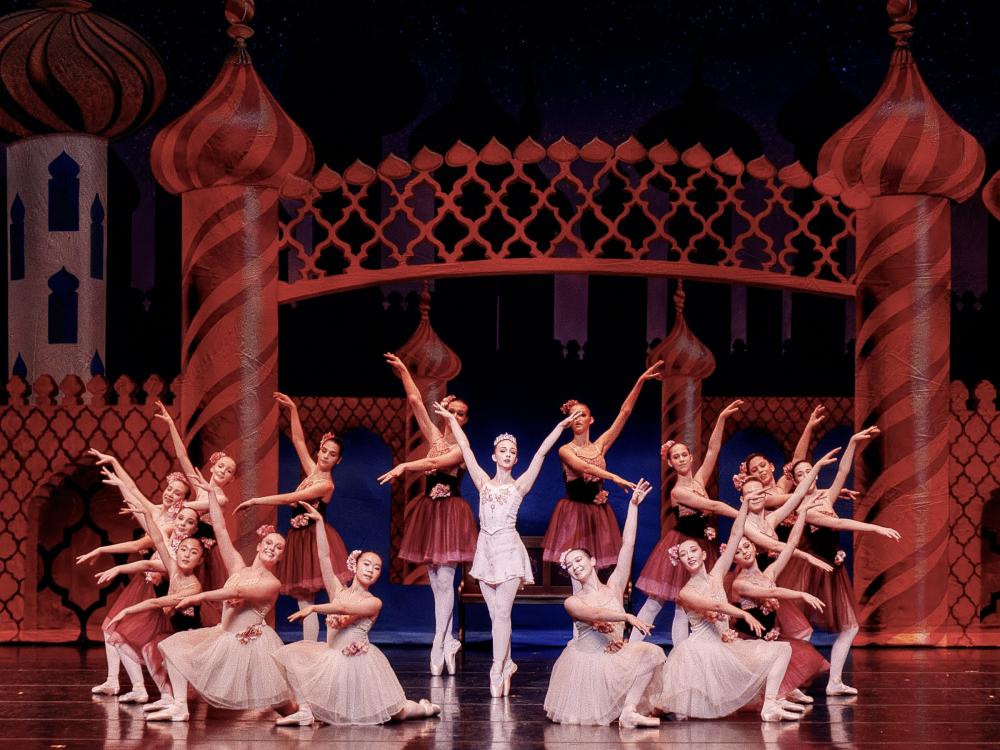 A group of young ballet dancers stand in formal poses.