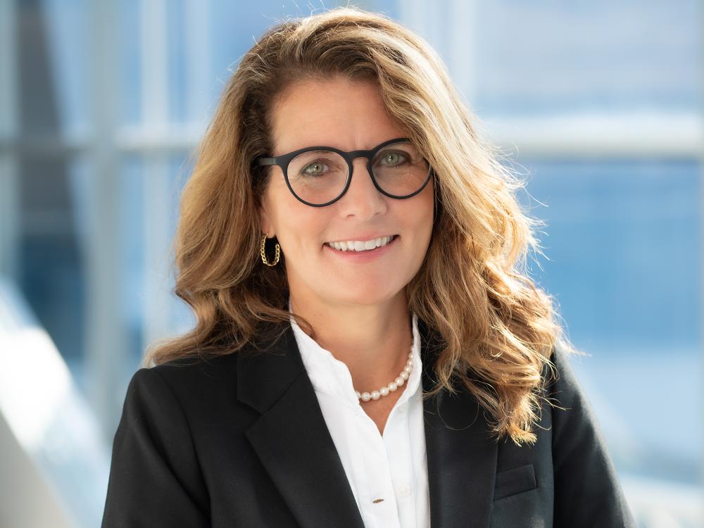 A headshot photo of a person in a suit with glasses
