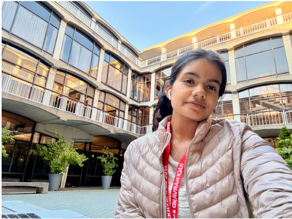 dark-haired student in winter coat in front of college building