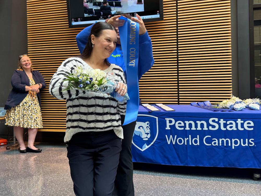 A woman puts a sash on another woman.